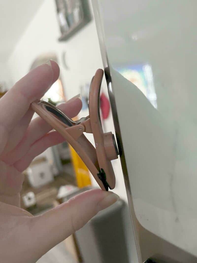 Clothespin attached to a whiteboard, holding a piece of paper at an odd angle.