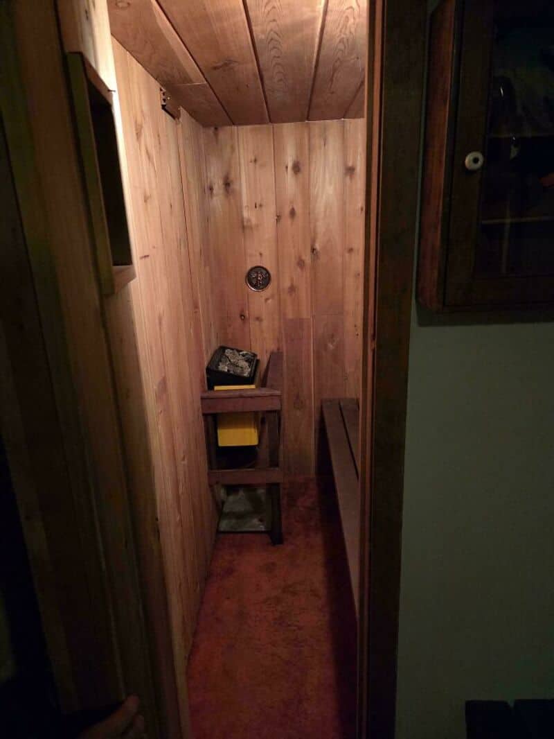 Small wooden room with a toilet paper holder and a small shelf with a yellow box.