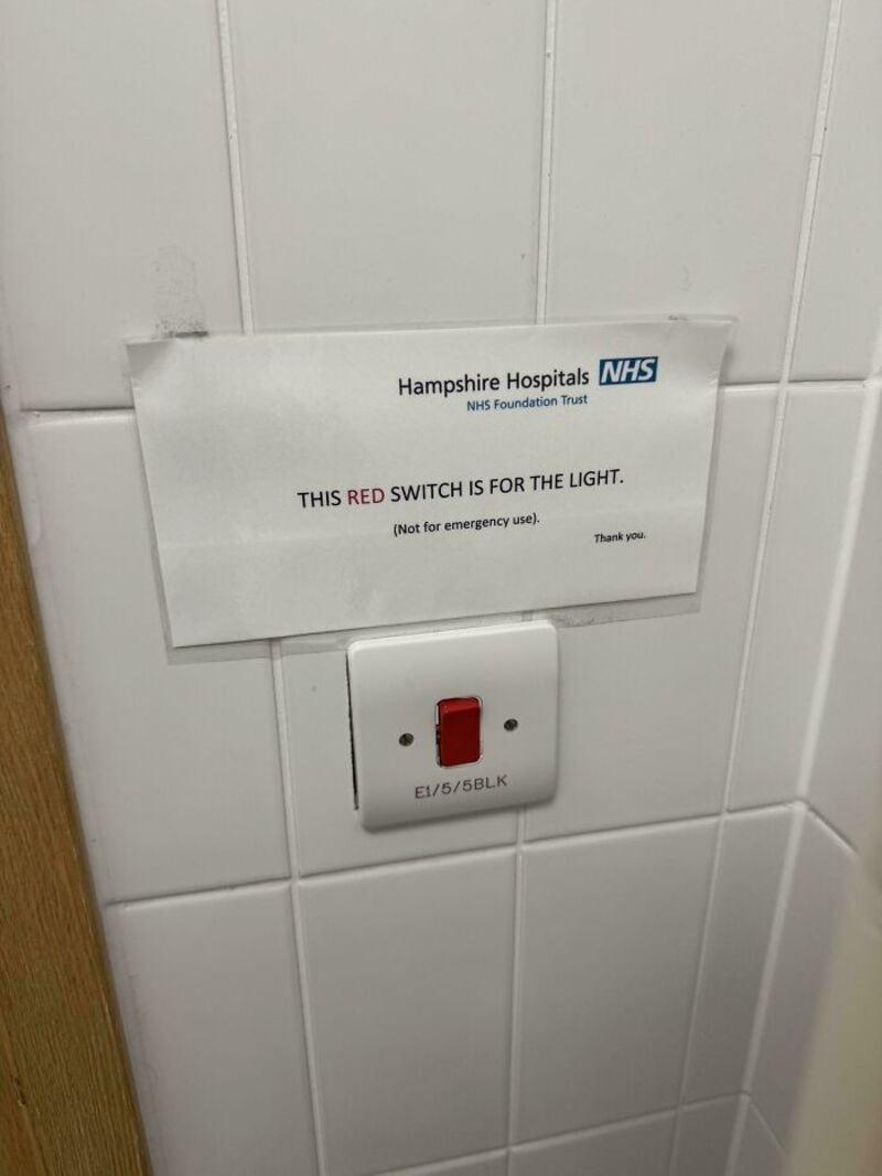 Red switch on wall with sign saying it's for the light, not for emergency use.