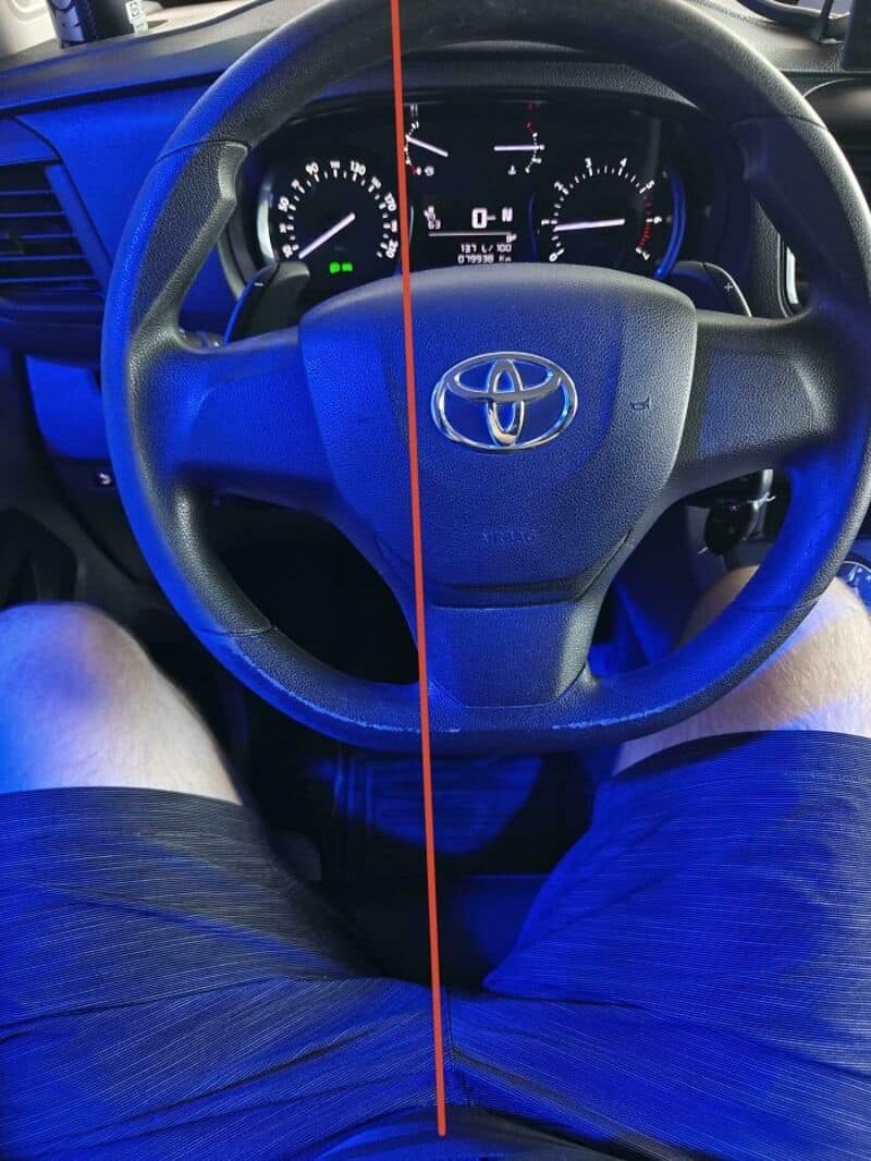 Car dashboard with steering wheel and instrument panel, split by a red line.