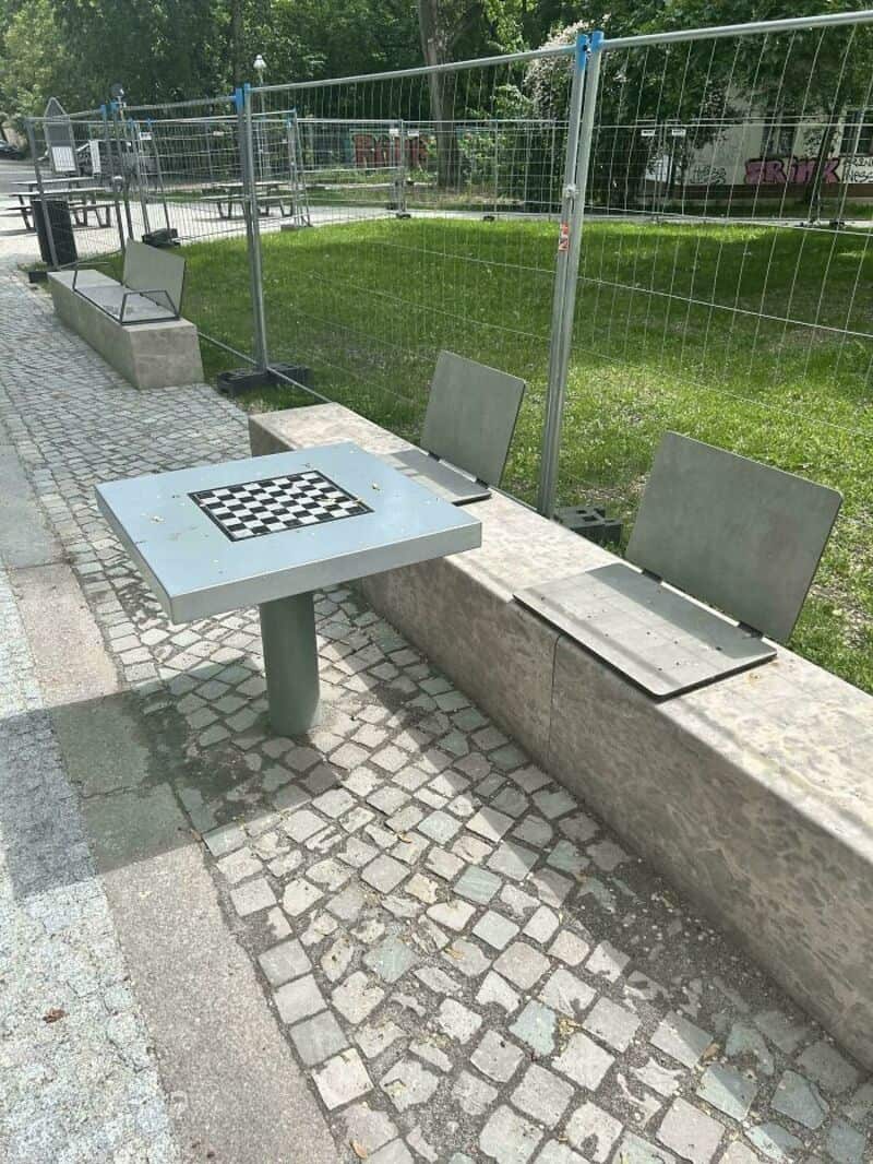 Unusual park bench with a chessboard table and two chairs with backrests.