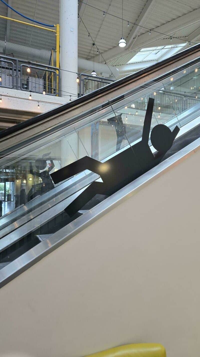 Black silhouette of a person lying on an escalator with arms raised.