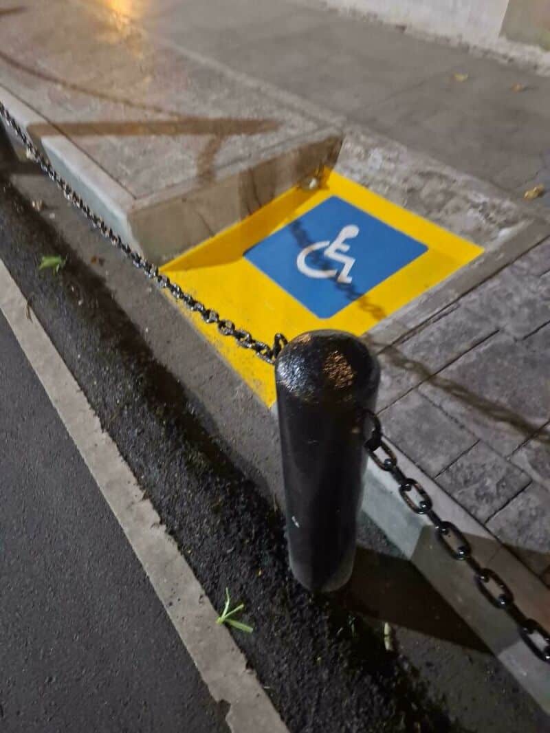 Disabled parking space with a chain barrier and a ramp.