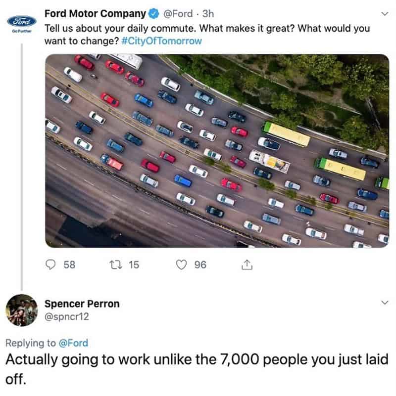 Aerial view of a busy highway with many cars and buses, surrounded by green trees.