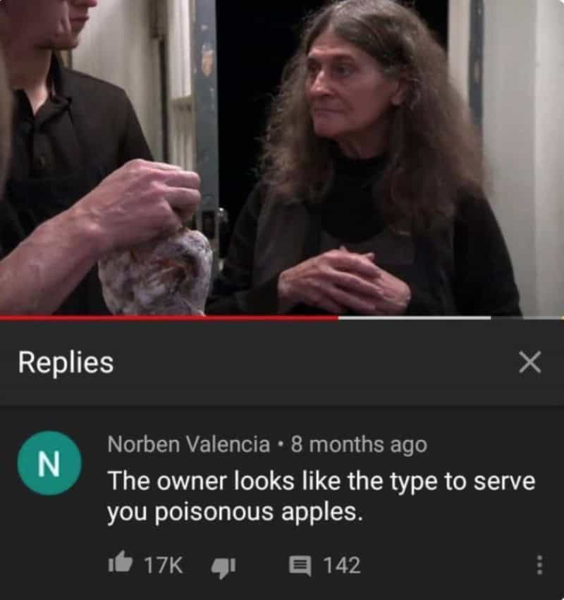 A woman with long brown hair looks at a person holding a bag of apples.