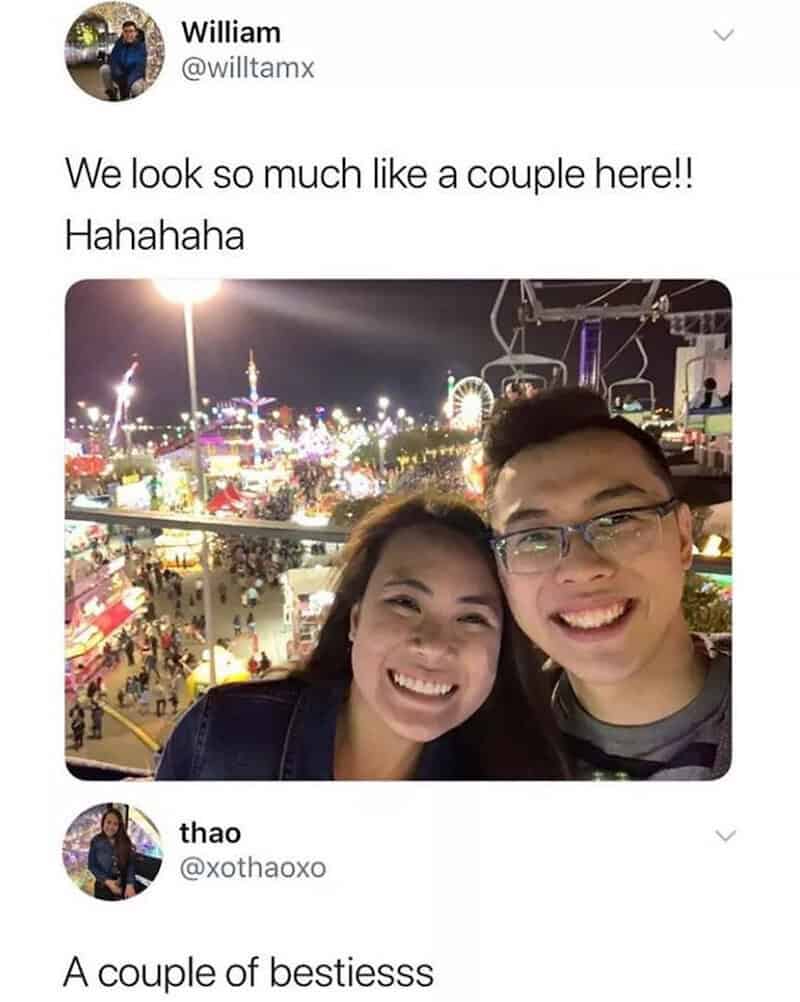 A smiling couple at a carnival with bright lights and rides in the background.