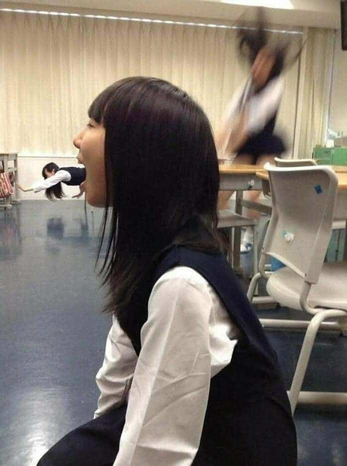 Girl with head in a desk, with a person falling in the background.