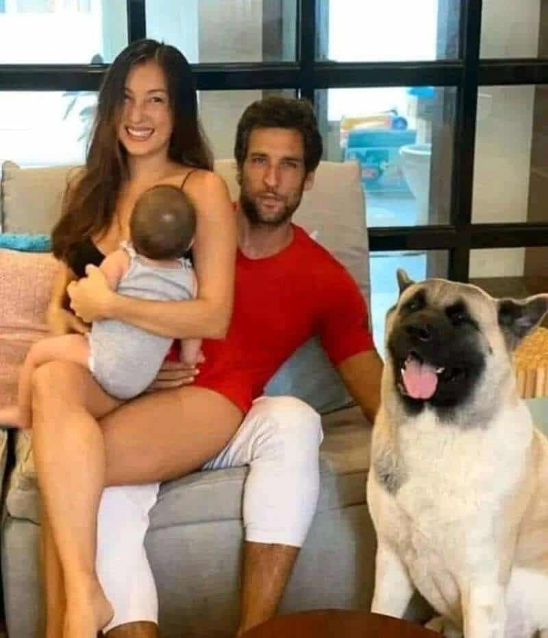 Happy family with a woman, man, baby, and dog in a cozy room.