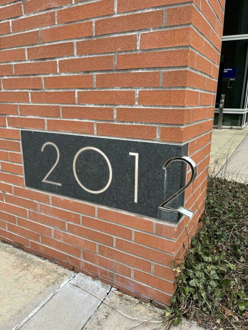 Number 2012 on a brick wall with a metal 2 leaning against it.