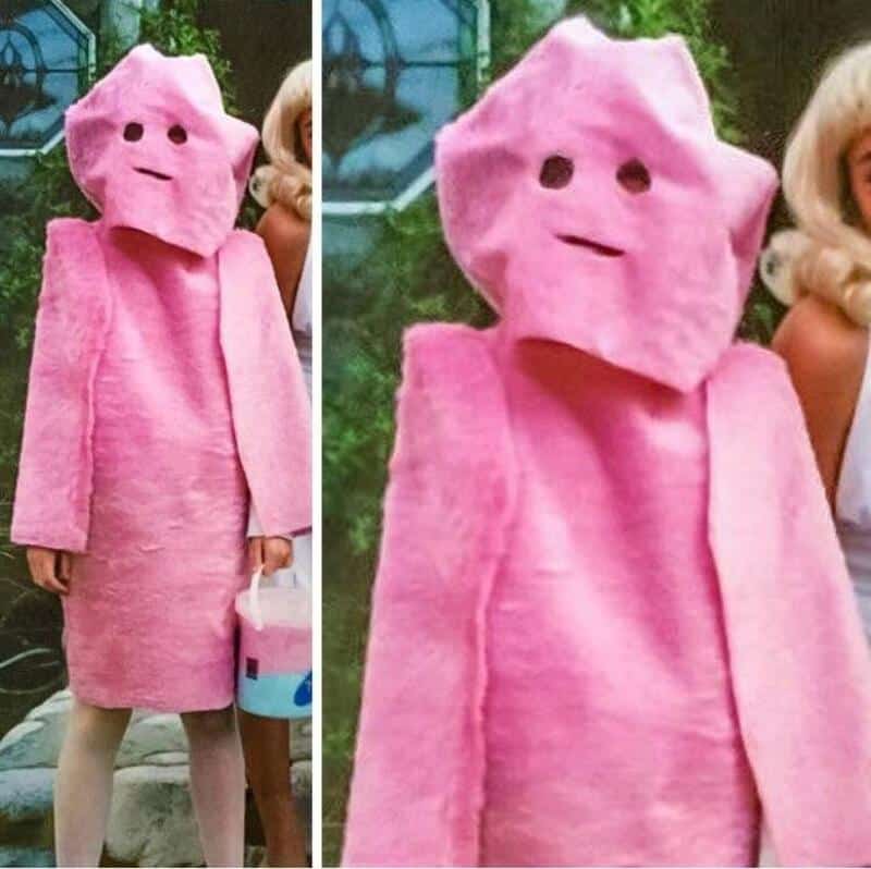 Woman wearing pink square-head costume with cape, holding small bucket; two-panel image shows person.