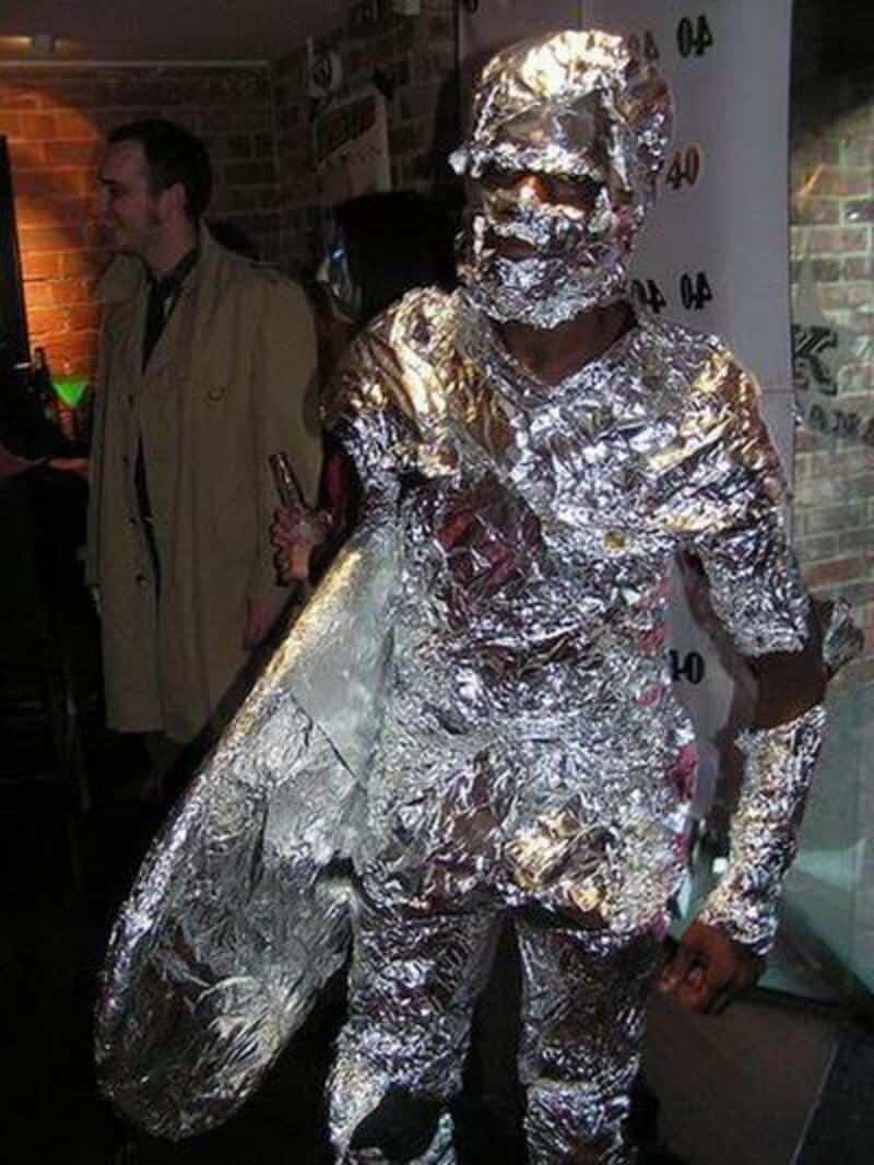 Man dressed in full reflective foil armor at Halloween event, holding a large shield.