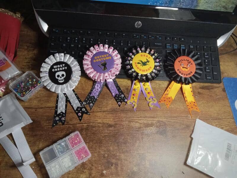Four Halloween-themed ribbons with funny labels on a wooden desk.