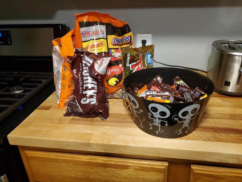 Halloween candy in a black skull and skeleton bowl on a kitchen counter.