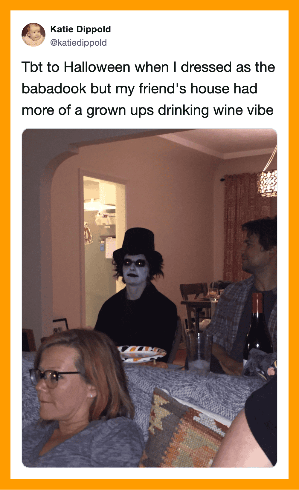 Person dressed as a spooky clown with face paint, top hat, and dark clothing at a Halloween party.