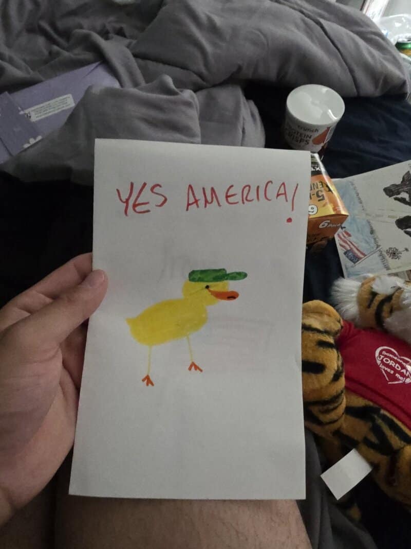 Yes America! handwritten card with a yellow duck drawing, green hat, and red text.