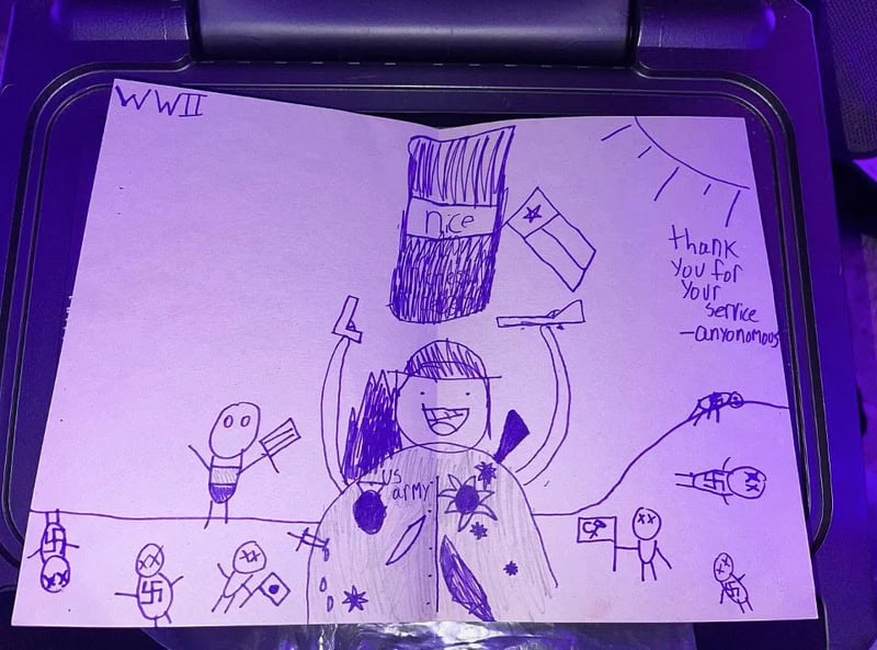 World War II scene with a central figure raising arms and a flag, surrounded by small drawings; sun,.