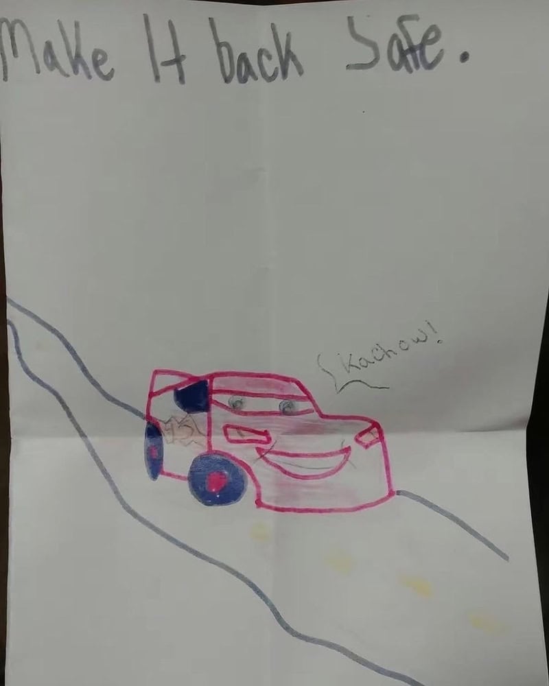 Make It back Safe. A pink toy car on a wavy road with a smiley face and scribbled text.