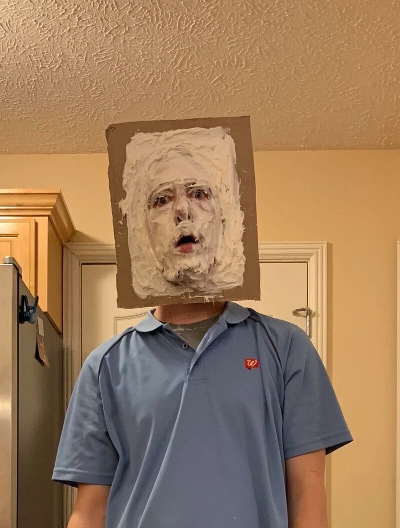 Person wearing a blue polo shirt with a mask-like face made of white textured material covering the头.