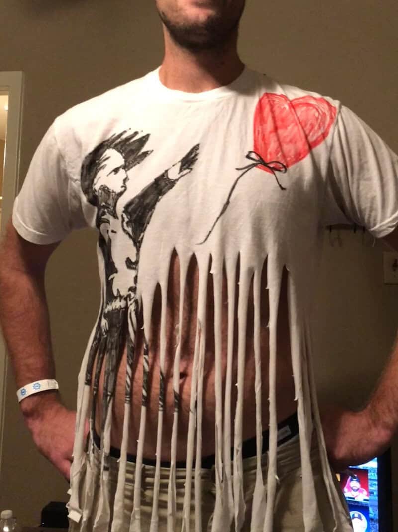 A man wearing a distressed white T-shirt with a graphic of a person pointing and a red heart balloon.