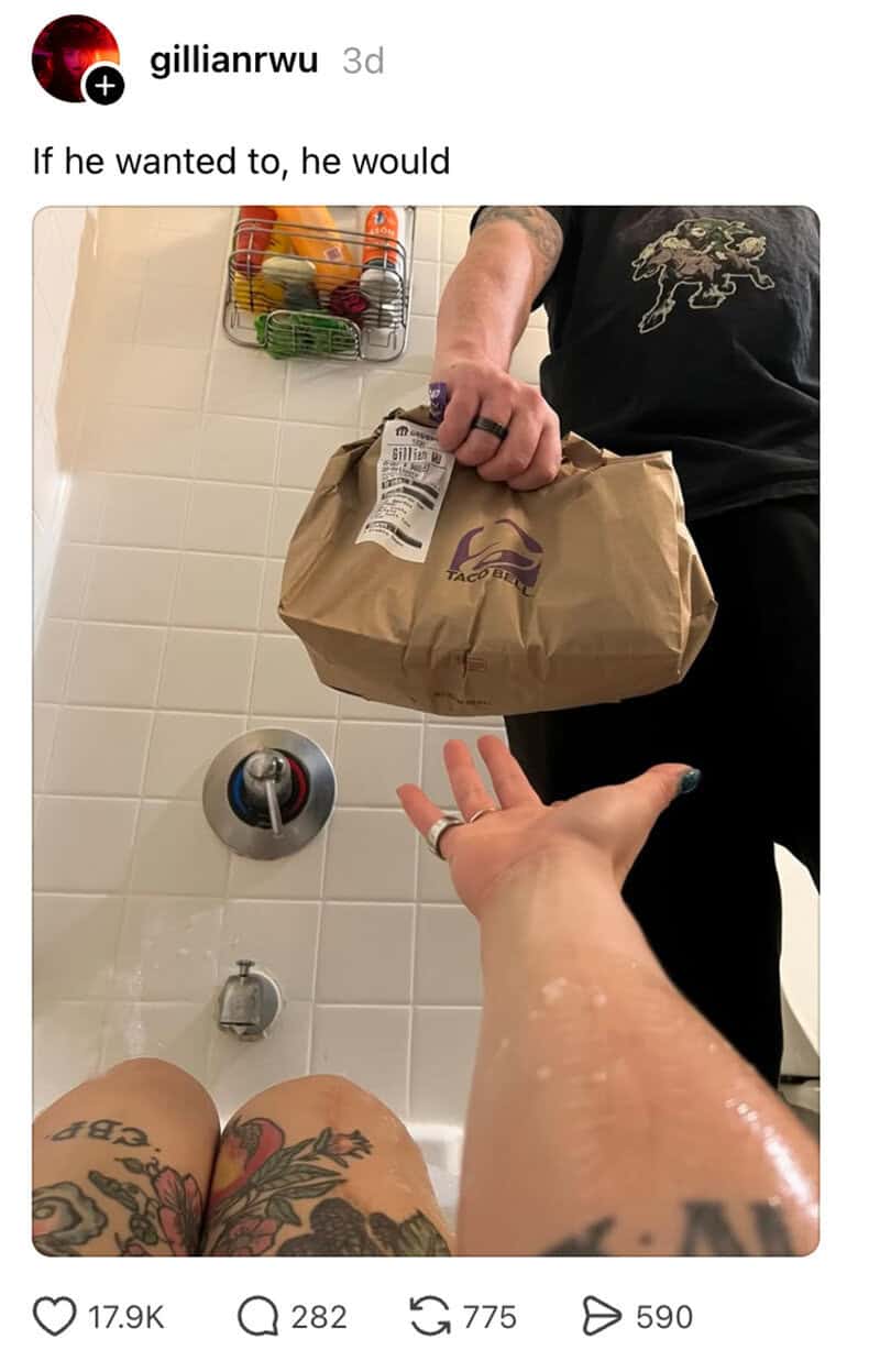 Person handing a paper bag to another person in a bathroom.