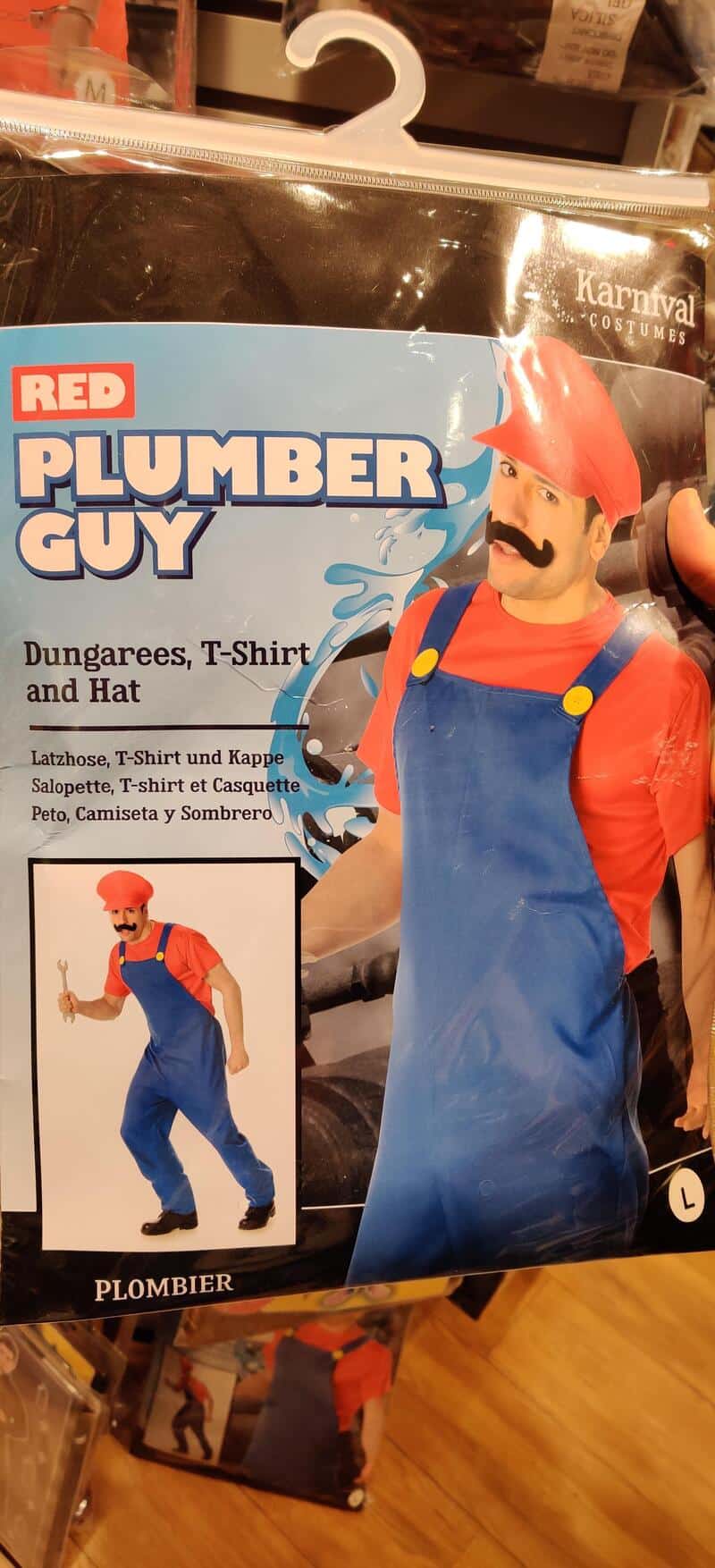 Red plumber guy costume with hat, blue overalls, and mustache, on store display.