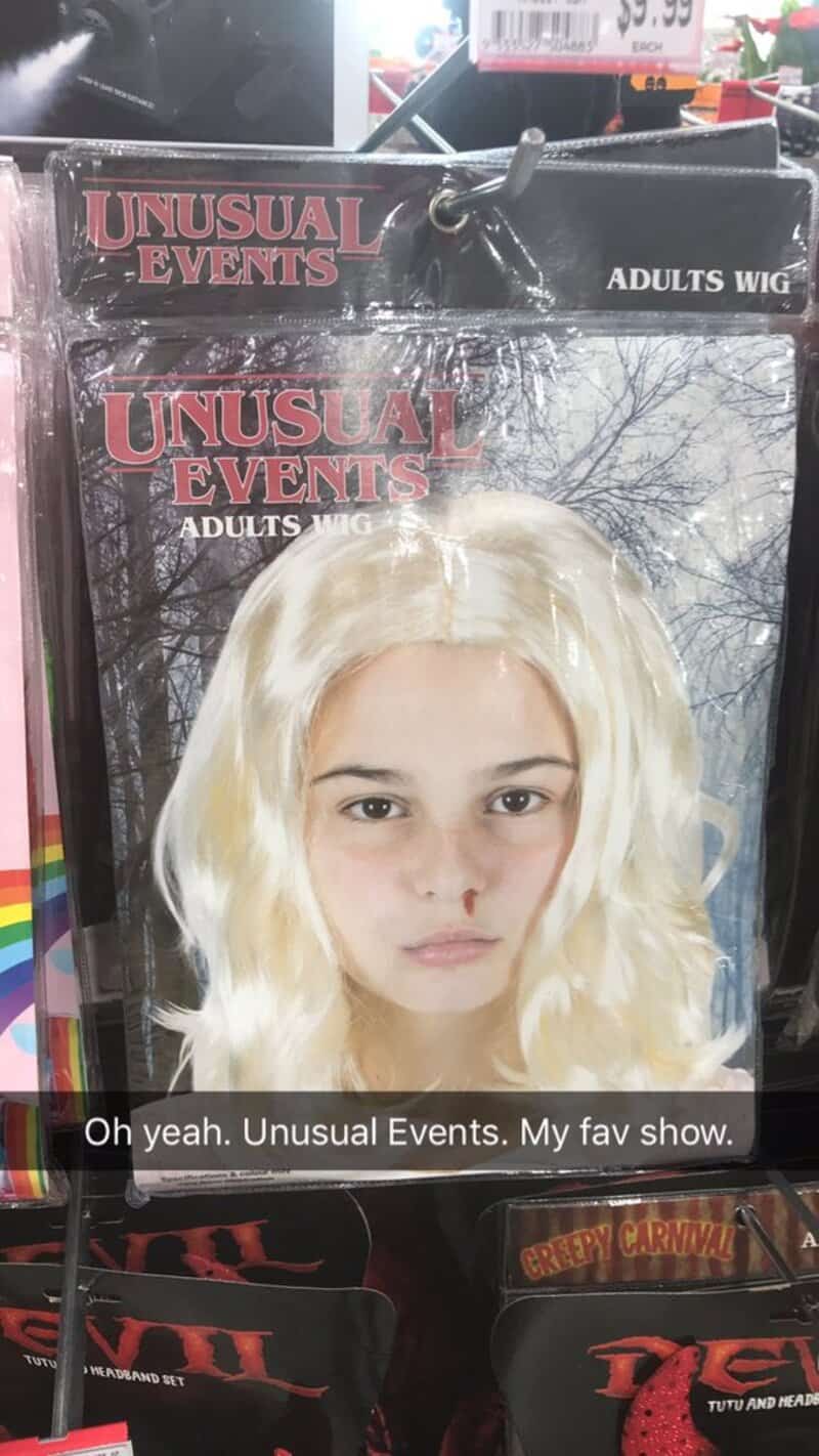 Adult wig with long blonde hair in packaging at store, Unusual Events brand.