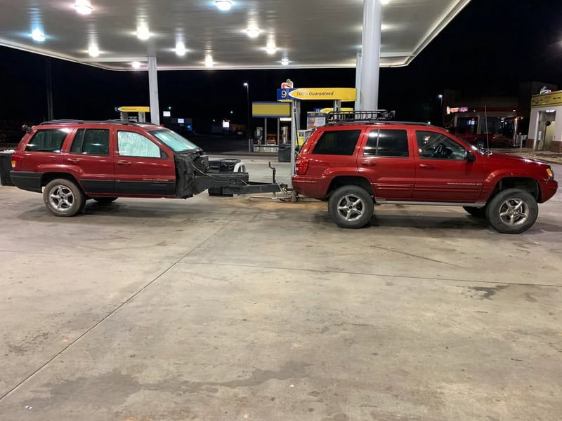 Red SUV with front damage connected to another red SUV at gas station.