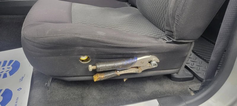 Modified car seat with a metal lever and yellow knob on the side.