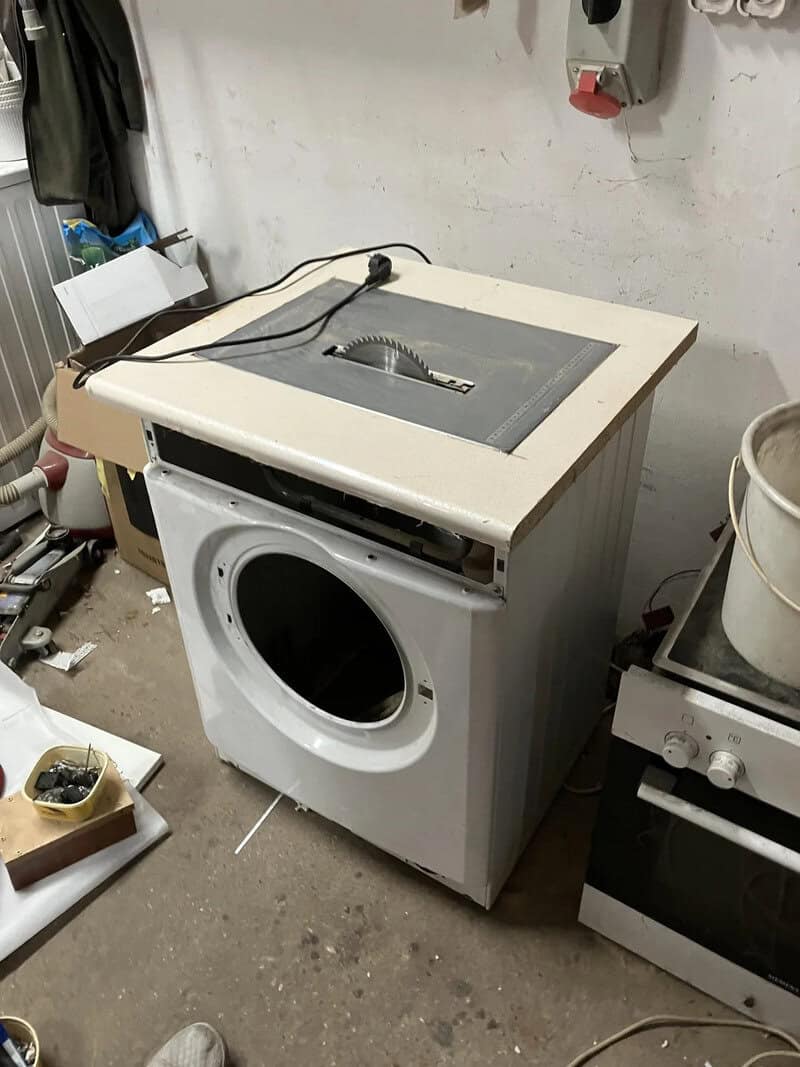 Washing machine with a table saw on top in a workshop.