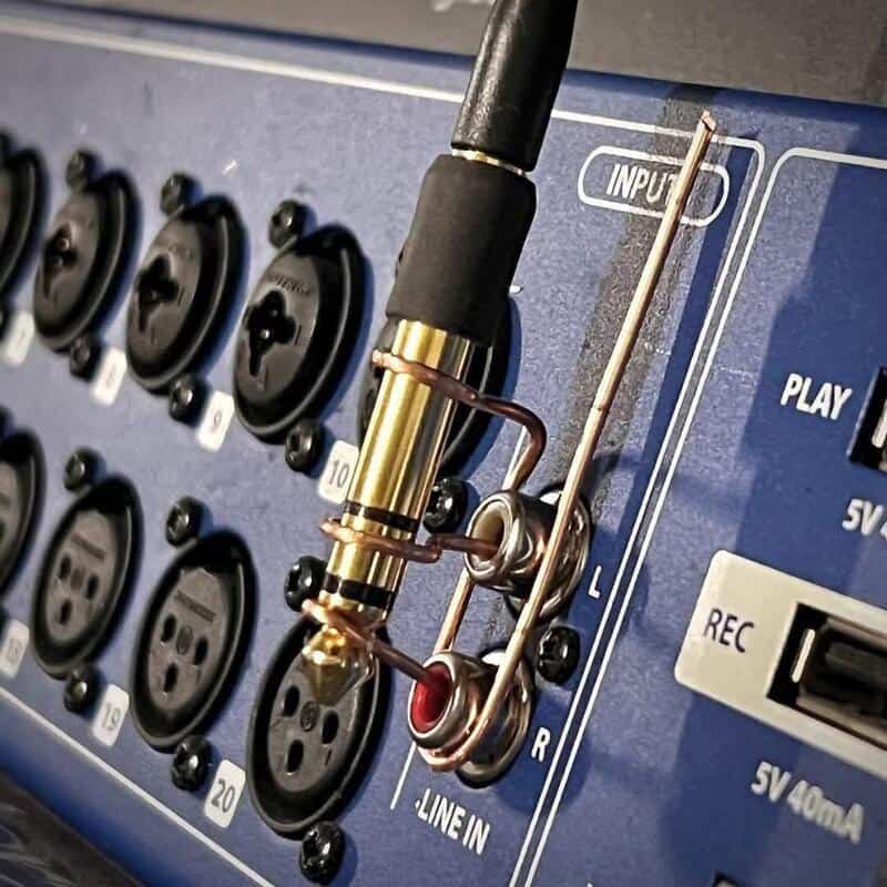 Audio equipment with a metal clip and wires connected to input jacks.