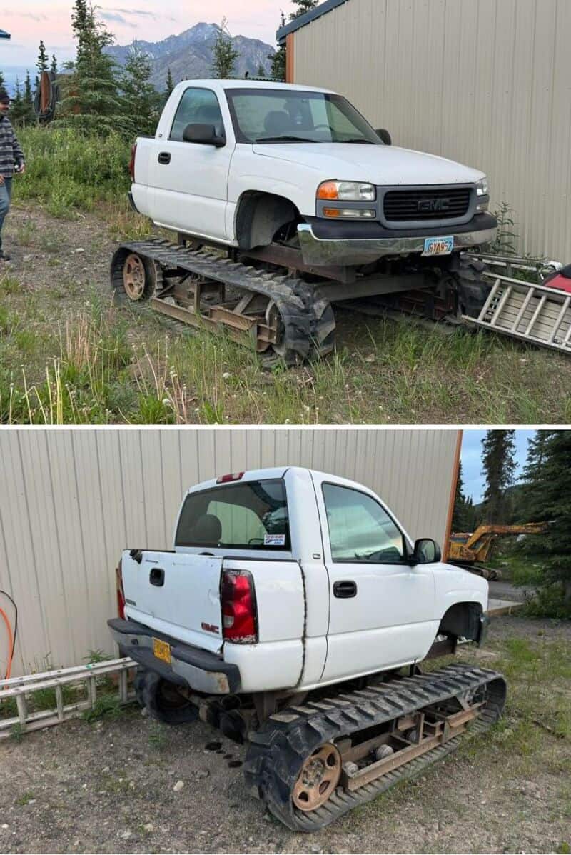White pickup truck with tank tracks instead of wheels, parked outdoors near a building.