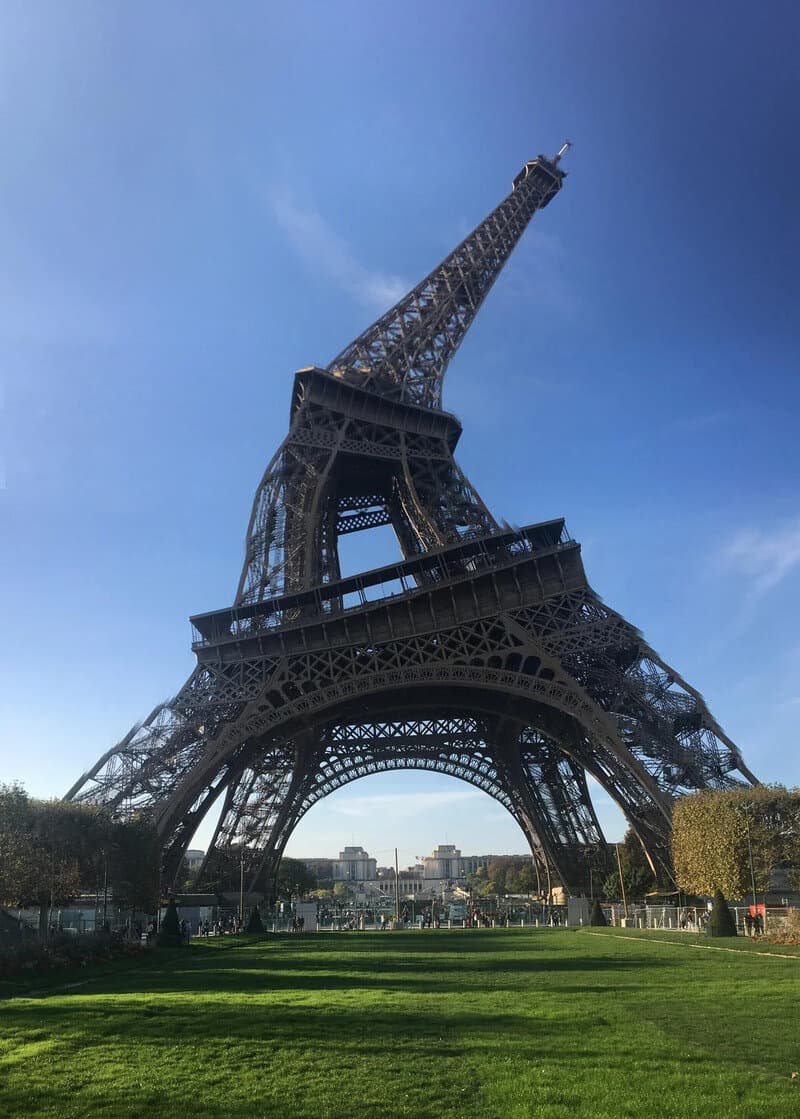 Eiffel Tower with a distorted, leaning appearance against a blue sky.