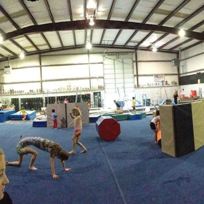 Children playing on gym equipment in an indoor facility.