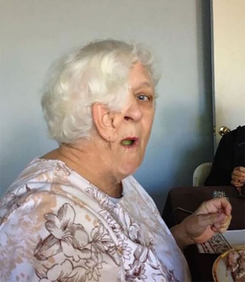 Elderly woman with white curly hair making a funny face in a panoramic photo.