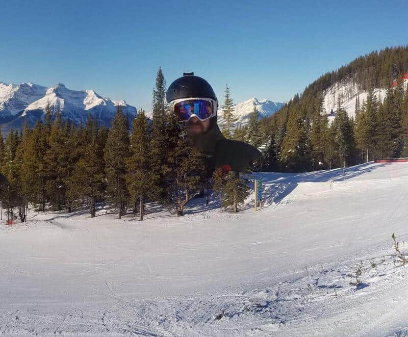 A skier in a black helmet and goggles appears to have a giant head due to a panoramic photo error.