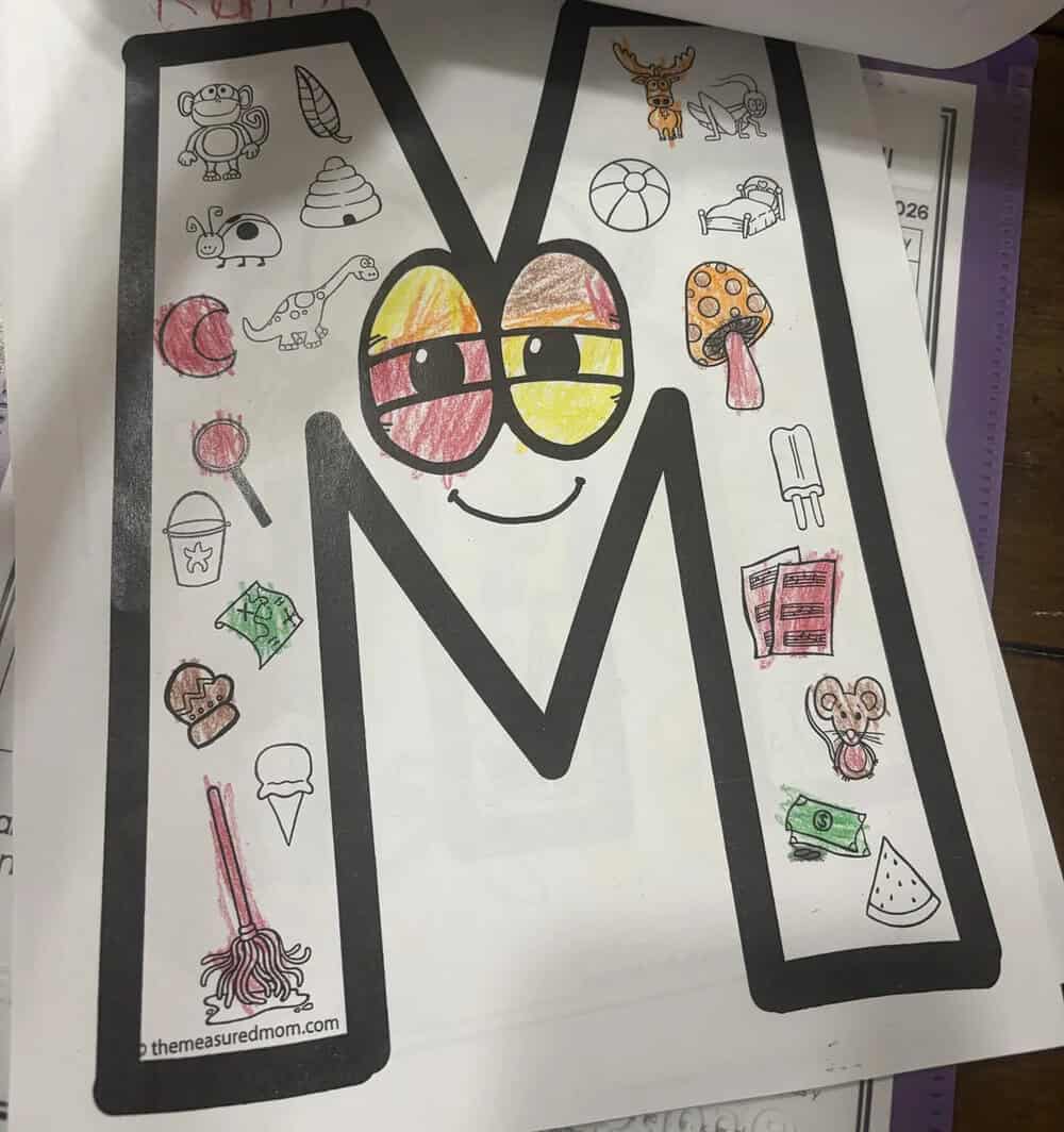Colorful letter M with a smiling face, surrounded by various doodles of objects and animals.