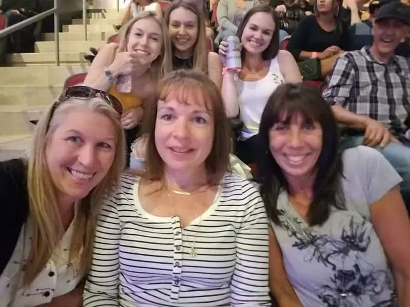 Group of women and a man at a concert, smiling and enjoying the event.