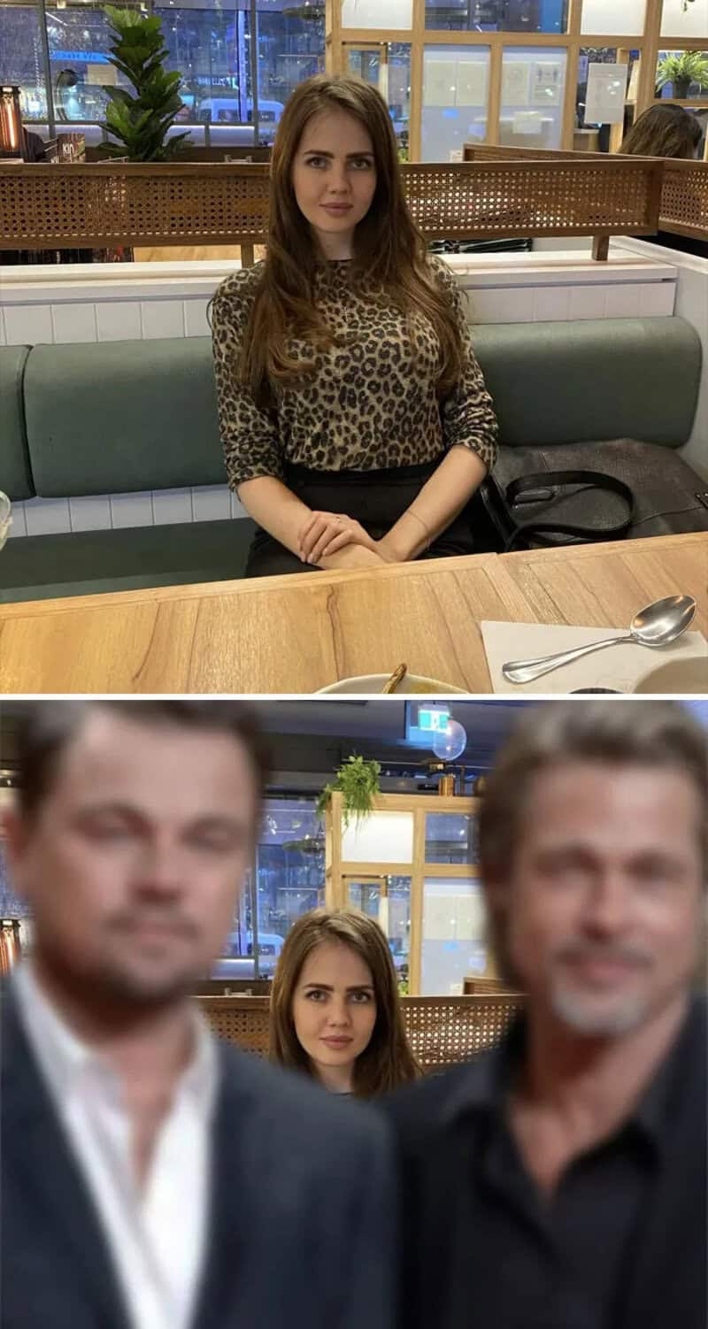 Woman sitting at a table with two men blurred in front, in a cafe setting.