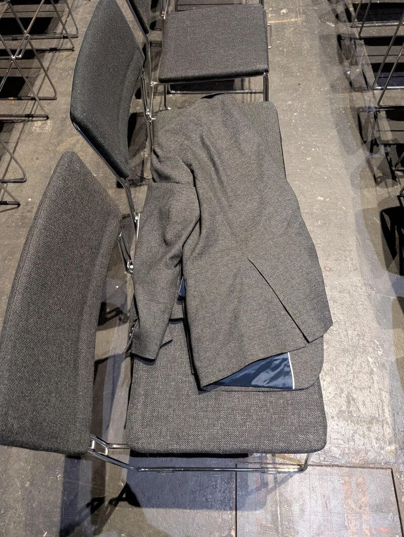 A gray suit jacket and pants draped over chairs in a conference room.