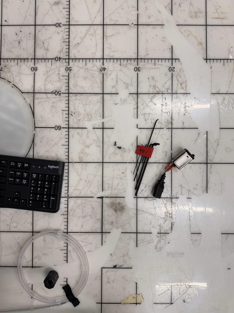 Tools and wires on a dirty cutting mat with grid lines and measurements.