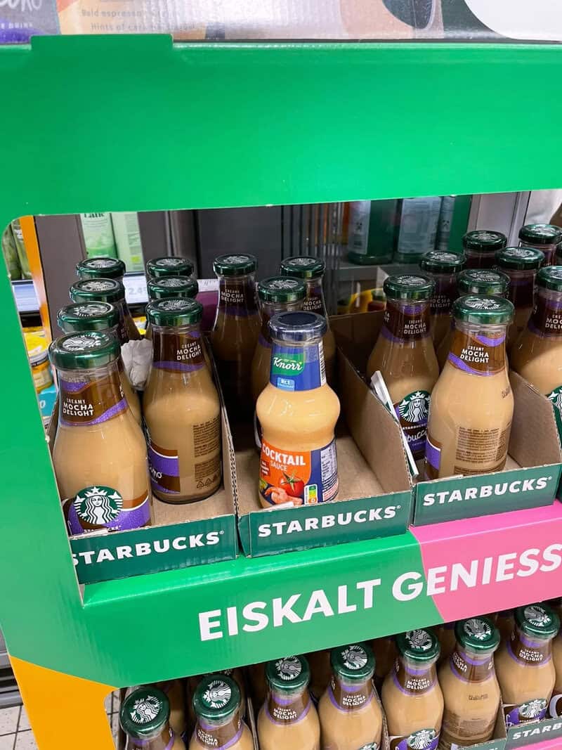 Starbucks Eiskalt Geniess coffee drinks on store shelf with green and pink packaging.