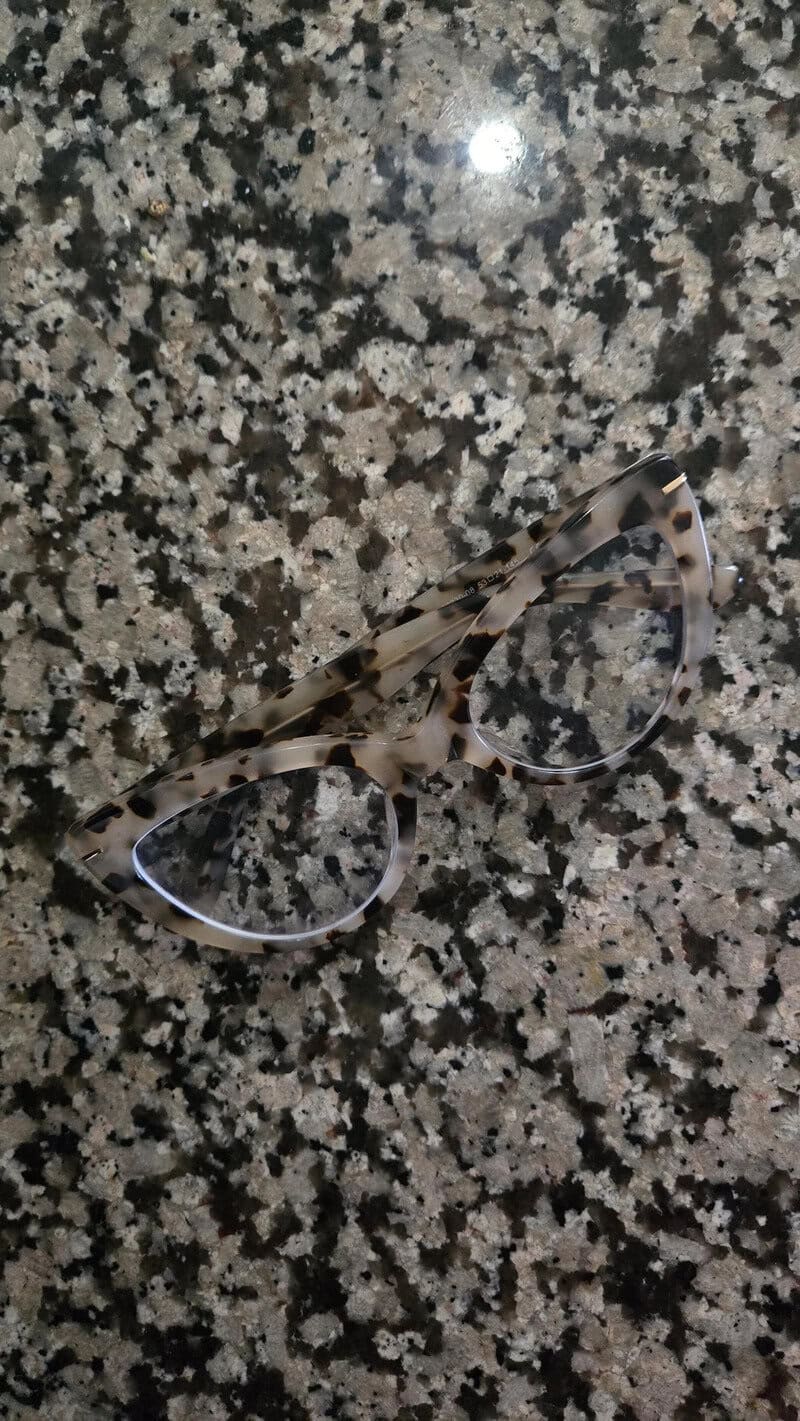 Eyeglasses on a speckled granite surface with a reflection of light.