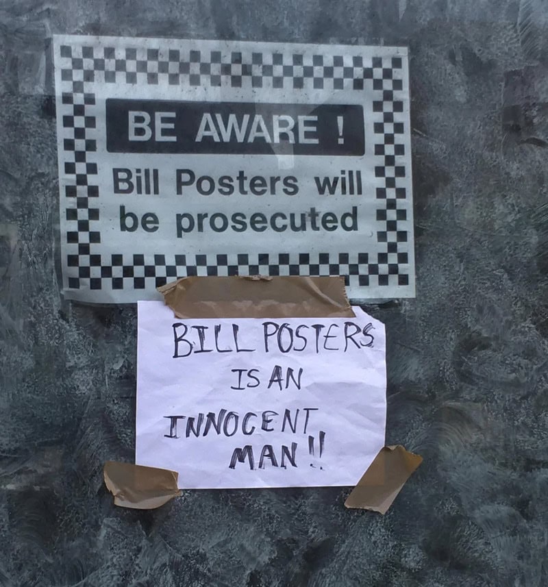 Warning sign about Bill Posters being prosecuted with a note calling him an innocent man.