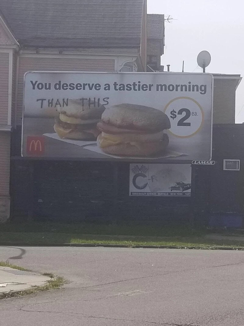 Billboard with McDonald's breakfast sandwich and handwritten 'THAN THIS' over it.