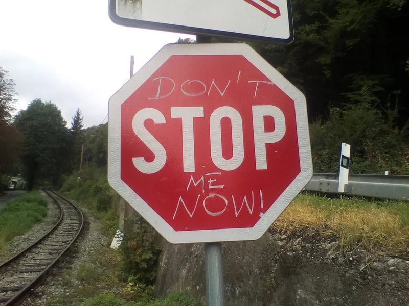 Graffiti on stop sign says 'DON'T STOP ME NOW!'.