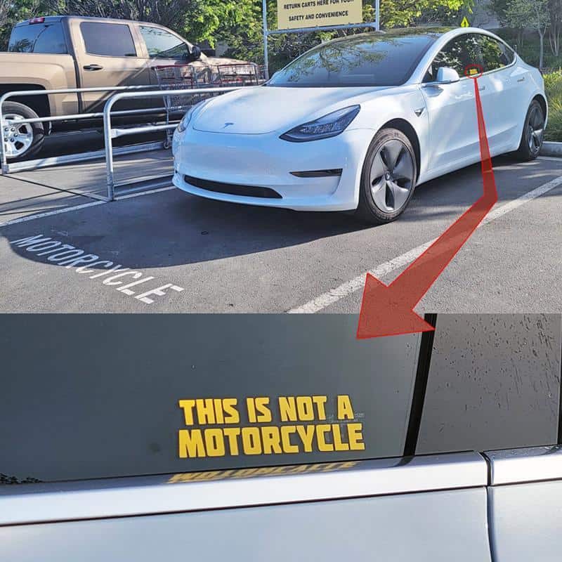 Car with a sign that says "This is not a motorcycle" in parking lot.