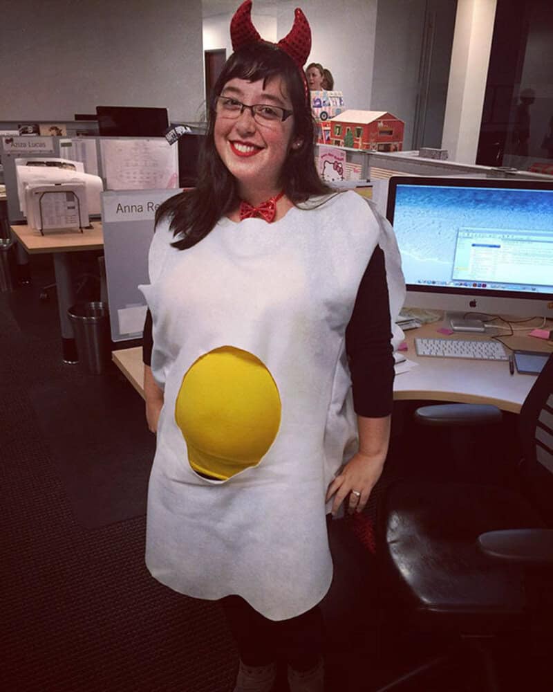 Woman in pregnancy costume with devil horns and a yellow belly button.
