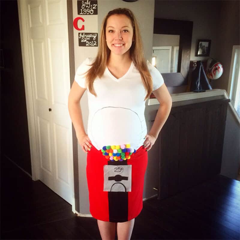 Woman in pregnancy costume with a toilet paper roll and colorful pom-poms on her belly.