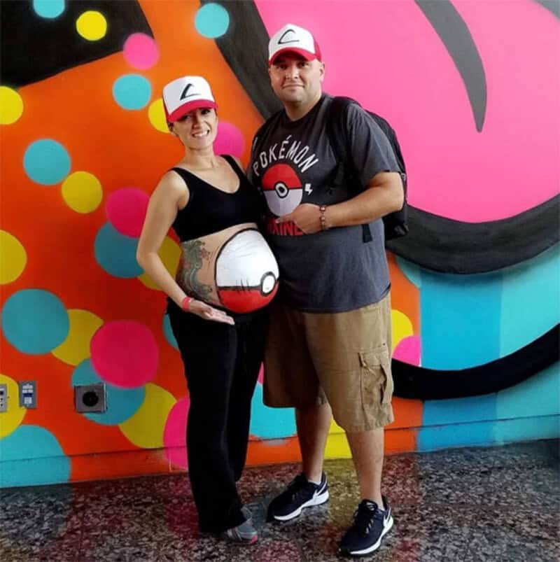 Pregnant woman and man with Poké Ball costume at Halloween event.