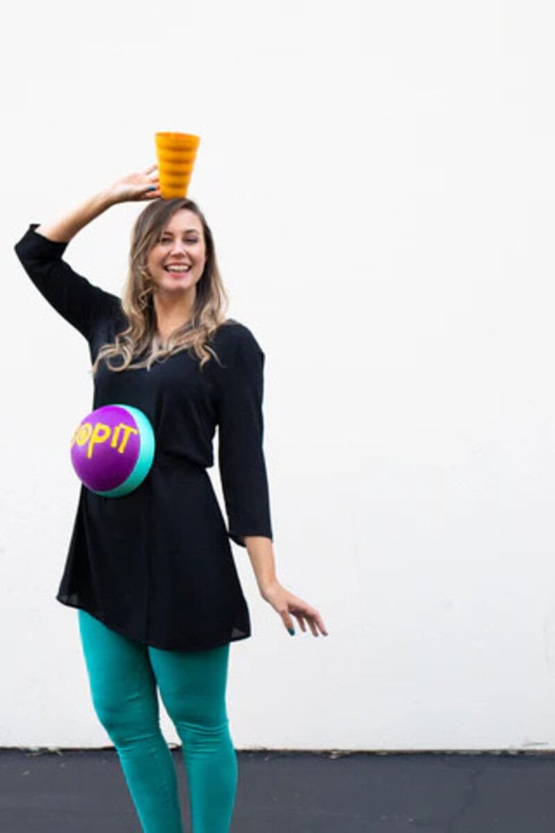 Pregnant woman in costume with a giant lollipop and ice cream cone, smiling.